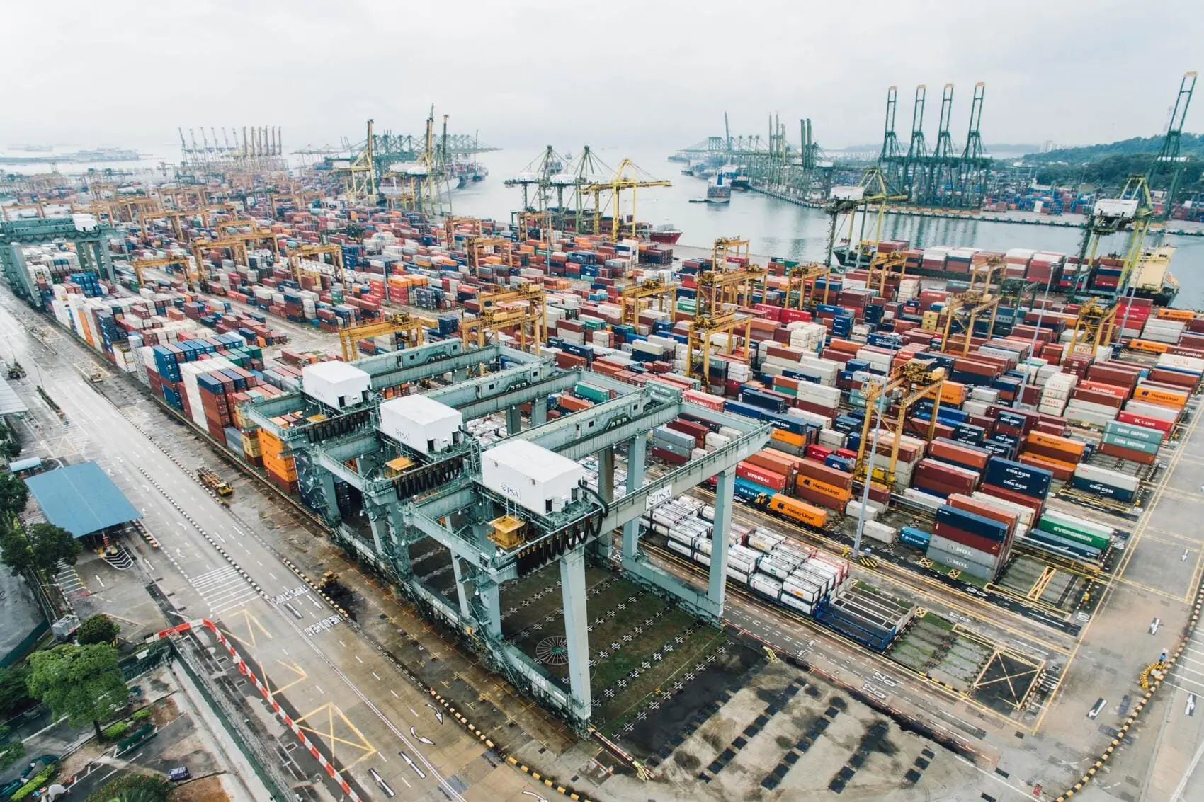 Aerial view of a container terminal with stacked containers and quay cranes.